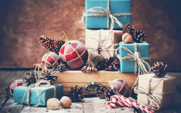 High-definition desktop wallpaper featuring a holiday still life with Christmas ornaments, candy canes, wrapped gifts, pinecones, and festive decorations.