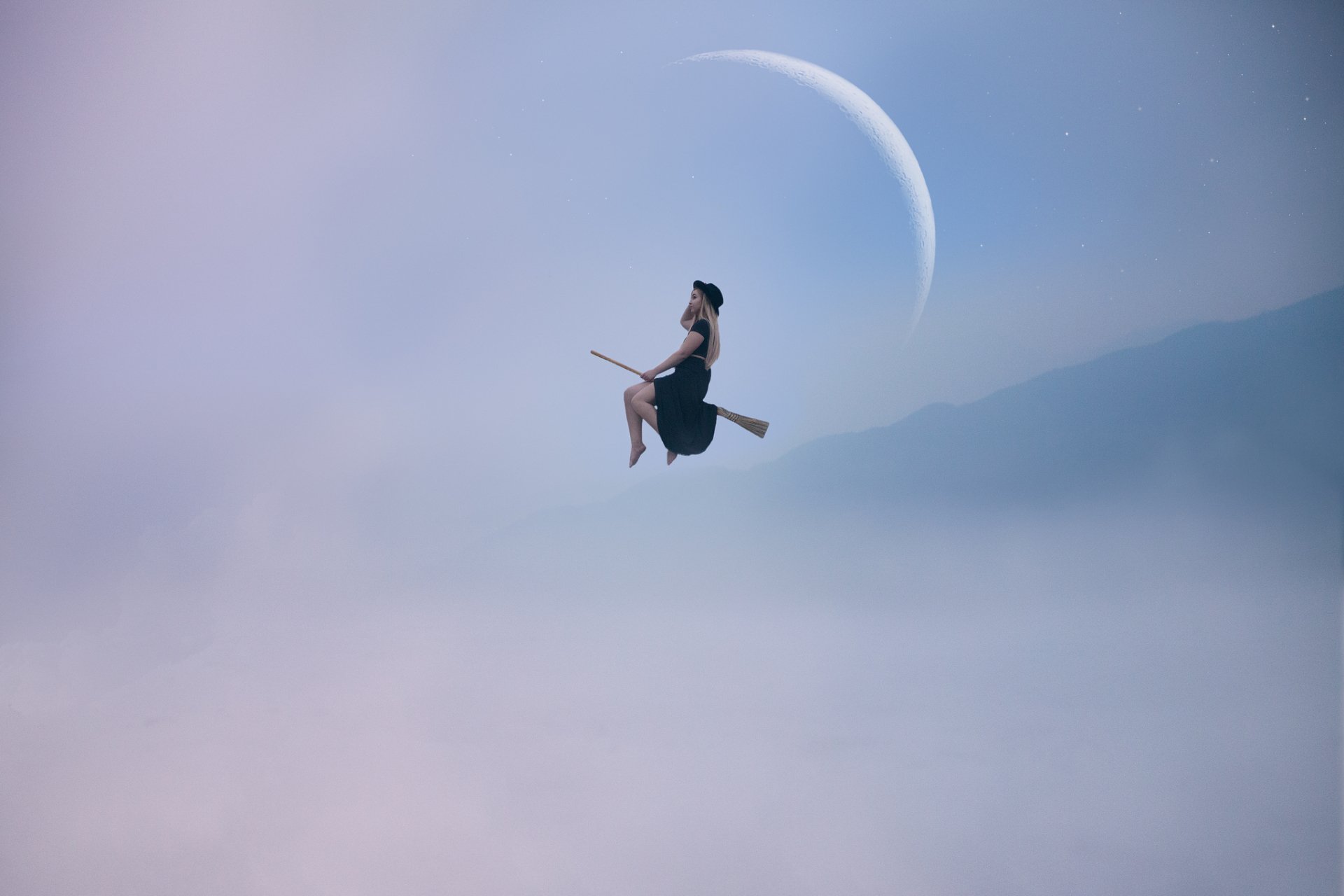 A woman in cosplay flies on a broomstick against a serene, misty backdrop with a crescent moon. HD desktop wallpaper.