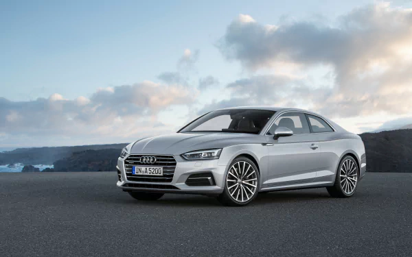 Silver Audi A5 coupe parked on an open asphalt plain under a dramatic cloudy sky — 4K Ultra HD PC desktop wallpaper background.