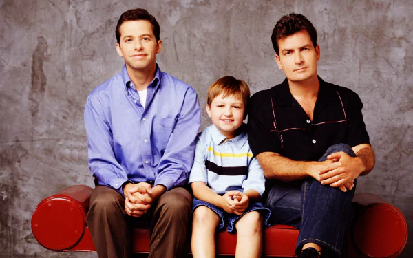 HD PC desktop wallpaper featuring the main cast of the TV show Two and a Half Men seated against a neutral background.