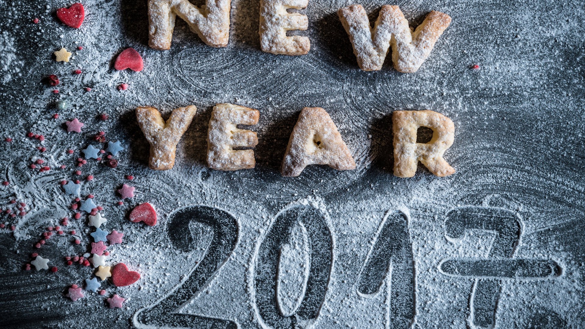 4K Ultra HD desktop wallpaper featuring cookies shaped as NEW YEAR and 2017 with holiday-themed sprinkles on a dark textured background.