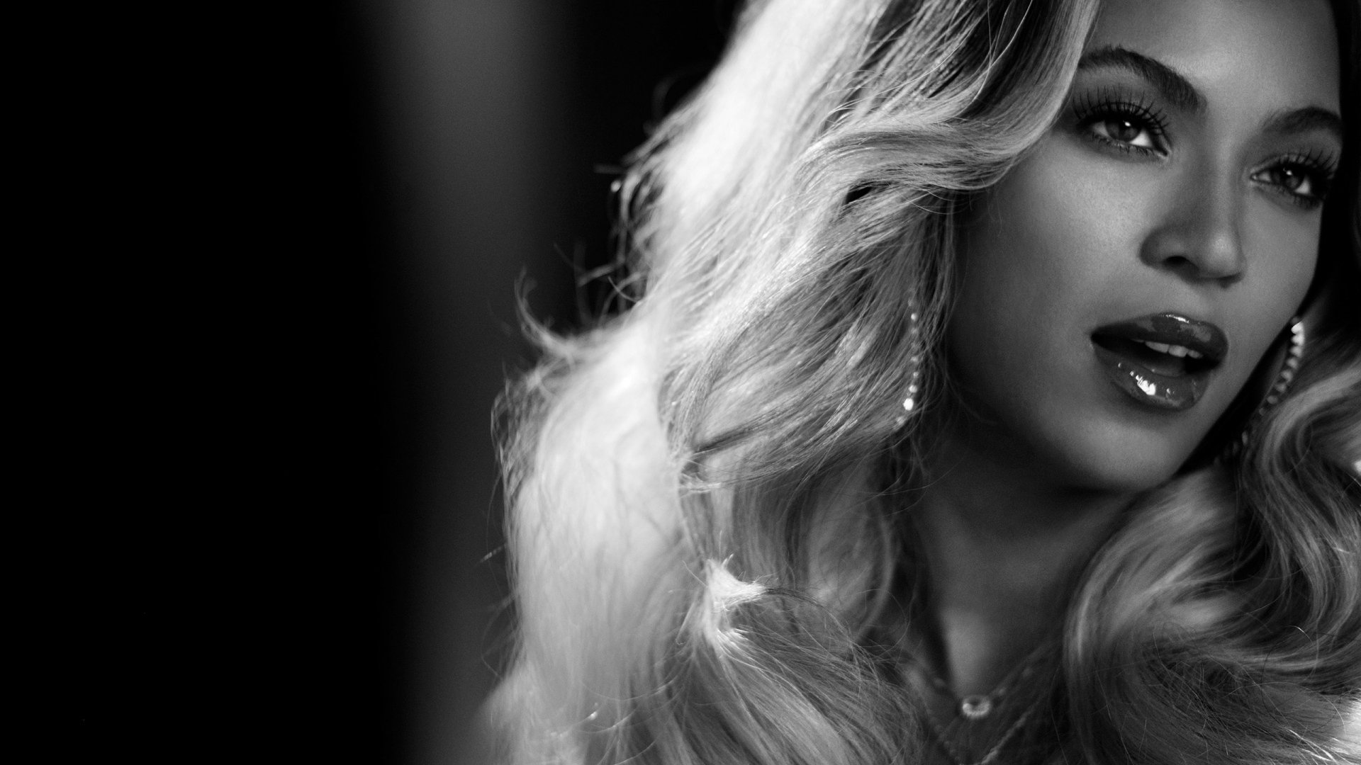 HD wallpaper featuring a monochrome portrait of a woman with wavy hair and glamorous makeup, providing an elegant desktop background.