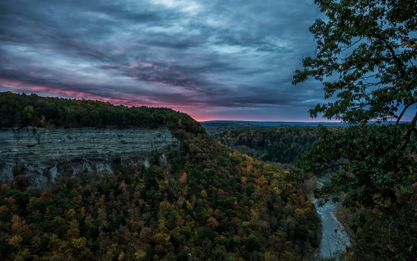 HD PC desktop wallpaper and background: panoramic nature landscape of Letchworth State Park and Wyoming — river winding through forested canyon and mountain cliffs under dramatic clouds.