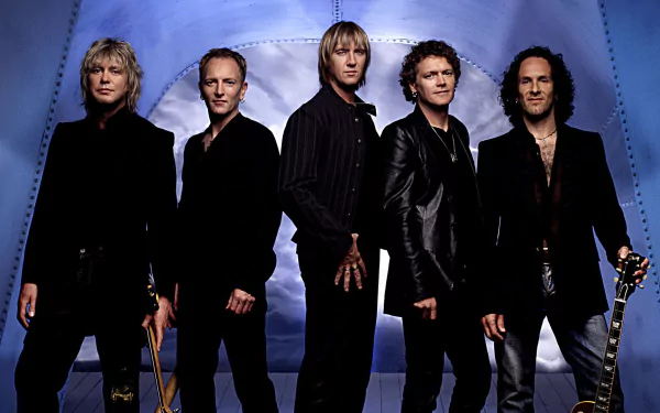 HD PC desktop wallpaper of a five-member hard rock/heavy metal band posing against a blue backdrop, wearing leather and holding guitars, projecting classic rock music energy.