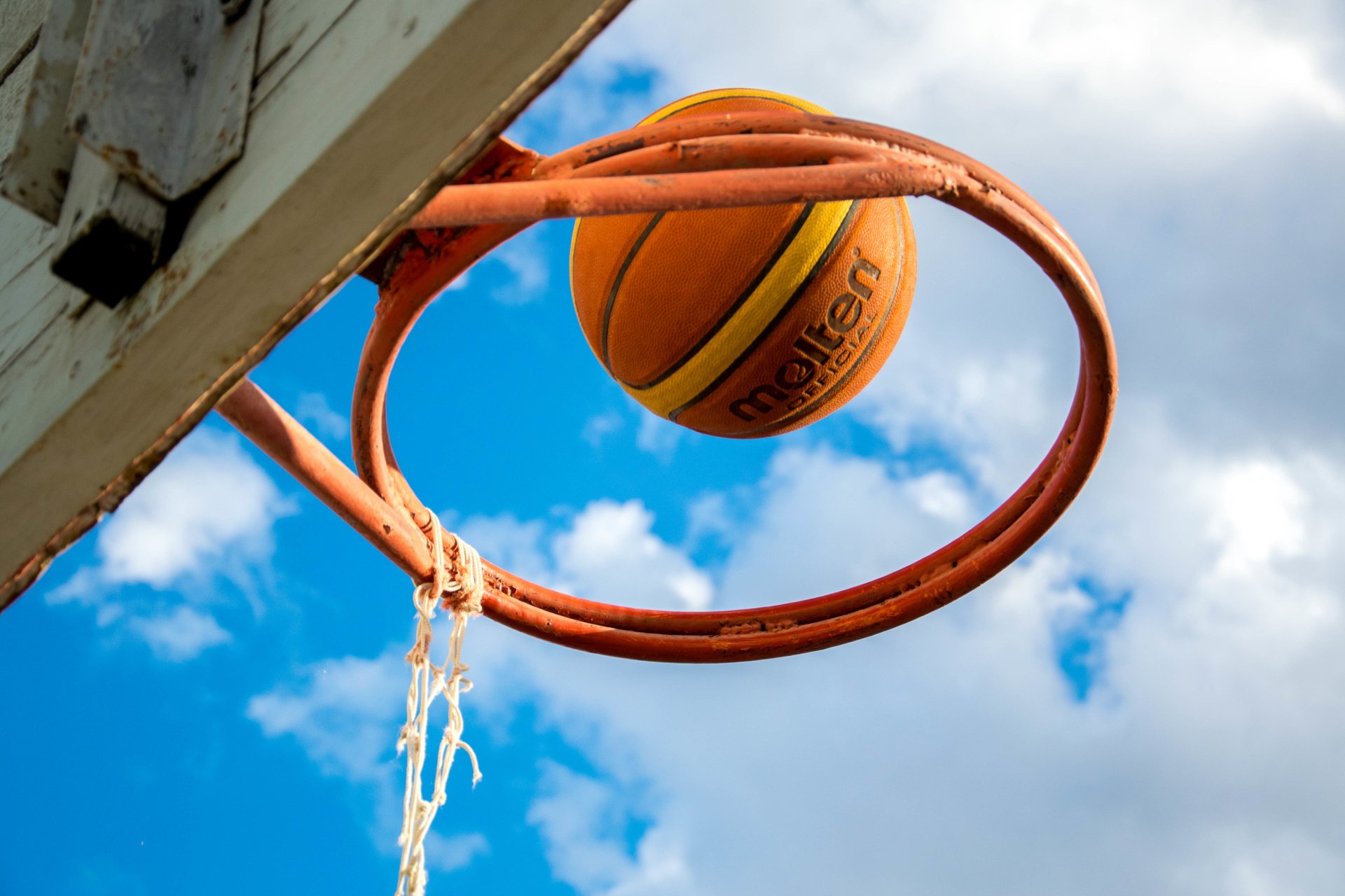 2K Quad HD PC desktop wallpaper showing a basketball swishing through an orange hoop against a bright blue sky; sports background.