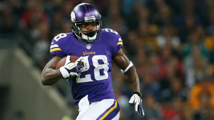 HD wallpaper of a player in a purple Vikings uniform with the number 28, in action on the football field.