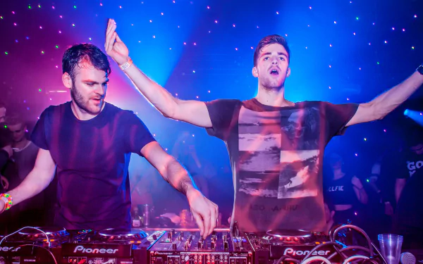 A vibrant HD desktop wallpaper featuring The Chainsmokers performing live, with colorful lights and an energetic atmosphere, capturing the excitement of their music.