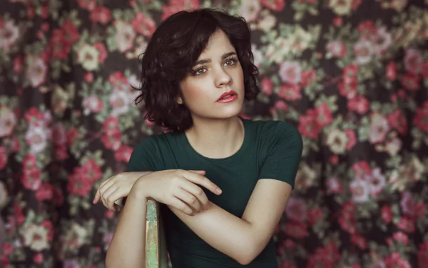 Portrait of a brunette woman with hazel eyes and lipstick, posing against a floral background, captured in HD quality for a desktop wallpaper.