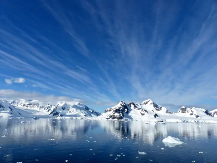 Paradise Harbor, Antarctica — blue sky with streaked clouds over snowy mountains and an icy bay with floating ice; 2K Quad HD desktop wallpaper.