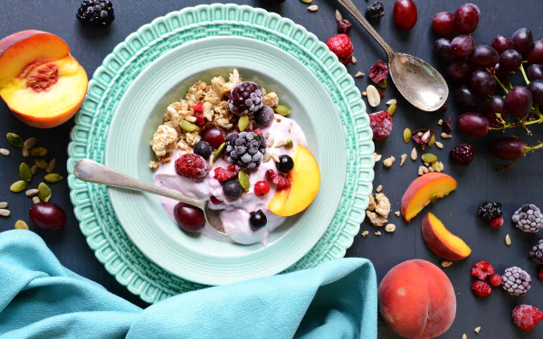 4K Ultra HD PC desktop wallpaper still life: bowl of yogurt and cereal topped with blackberries, raspberries, cherries and peach slices on a mint plate, with spoon and napkin nearby.