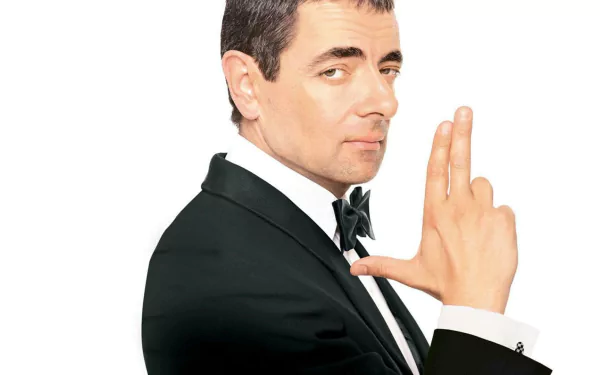 HD PC desktop wallpaper of a tuxedoed spy character from the movie Johnny English, striking a finger‑gun pose against a white background.