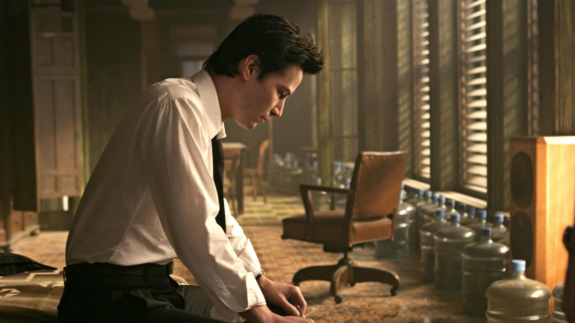 HD PC desktop wallpaper featuring a scene from the movie Constantine with a contemplative man in a white shirt and tie in a dimly lit room.