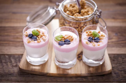 5K Ultra HD PC desktop wallpaper showing three glass cups of layered yogurt styled as food, topped with muesli and blueberries on a wooden board.