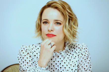 HD desktop wallpaper of Canadian actress Rachel McAdams with short blonde hair, wearing a white patterned blouse, against a light background.