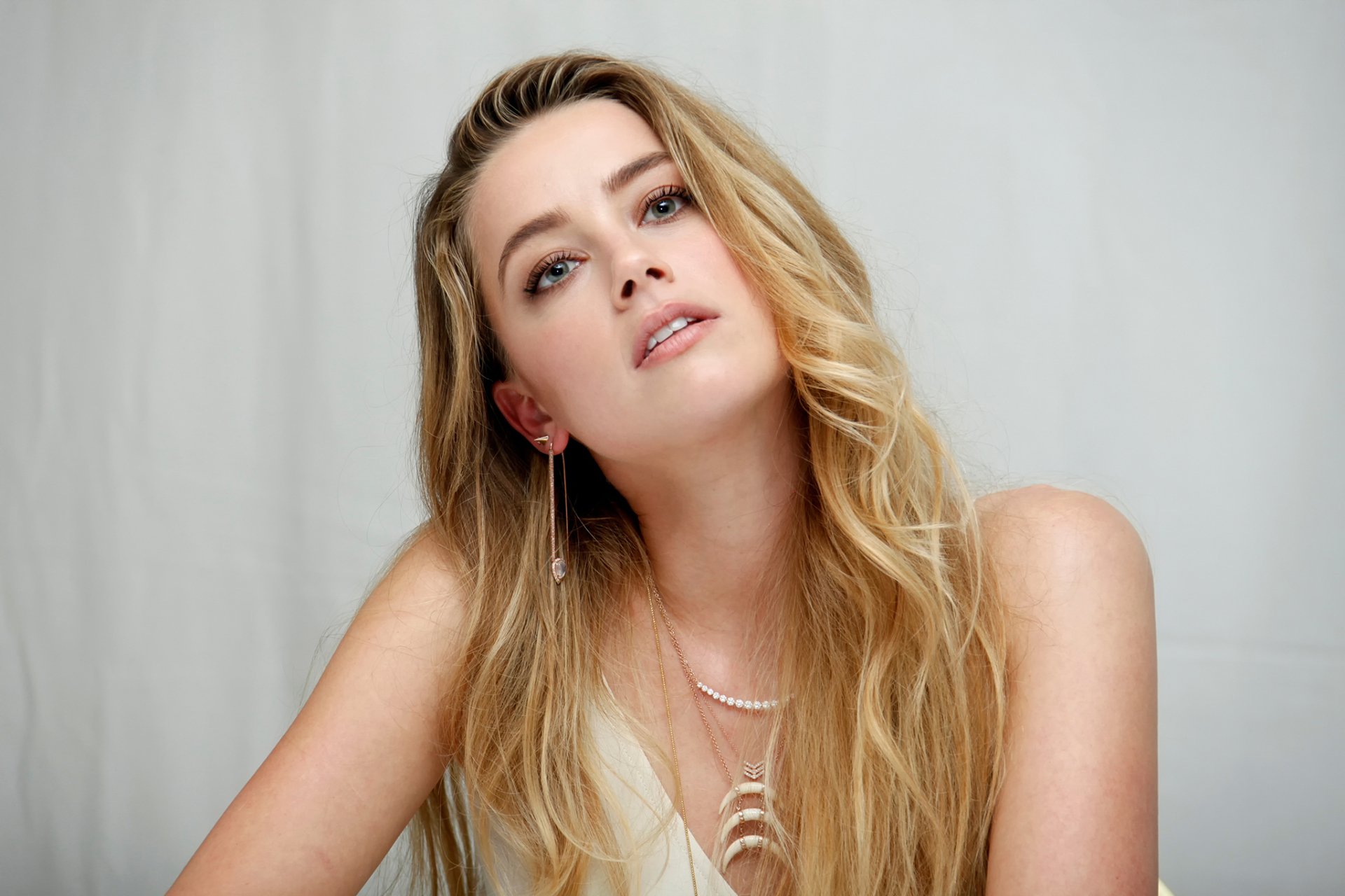 HD desktop wallpaper featuring a close-up of American actress Amber Heard with blonde hair and striking blue eyes against a neutral background.