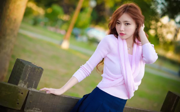 A high-definition desktop wallpaper featuring a redheaded Asian woman with brown eyes posing outdoors, with a blurred background adding depth of field.