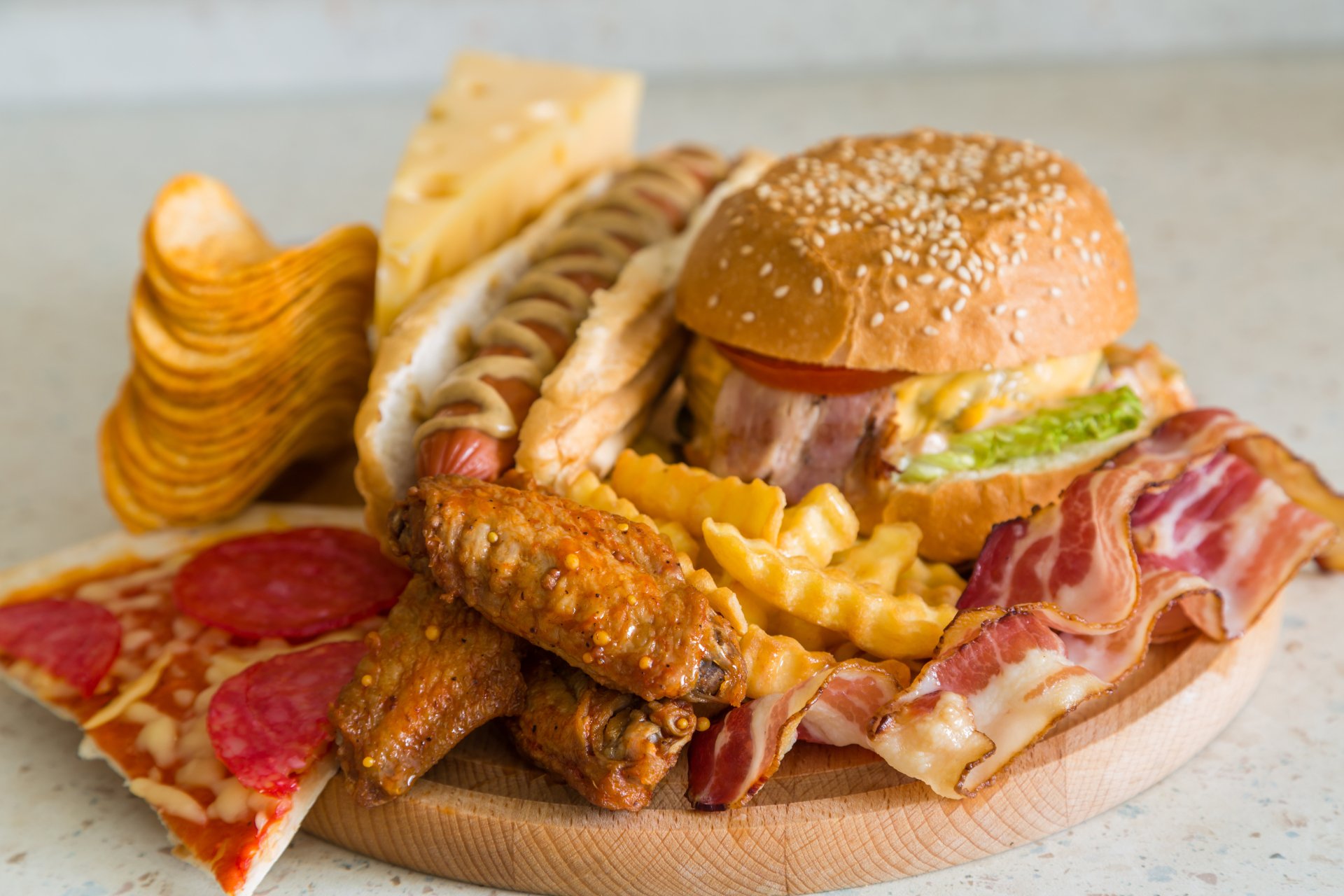 4K Ultra HD desktop wallpaper showcasing a delicious still life of pizza, burger, hot dog, crispy fries, bacon, chicken wings, and potato chips.