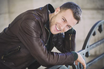 A smiling man wearing a leather jacket leans forward, captured in high detail as a 4K Ultra HD PC desktop wallpaper and background.
