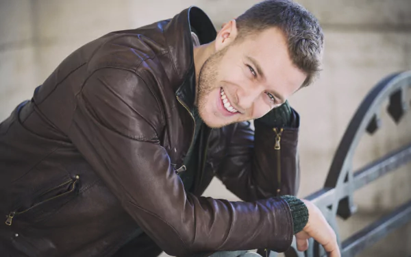 A smiling man wearing a leather jacket leans forward, captured in high detail as a 4K Ultra HD PC desktop wallpaper and background.