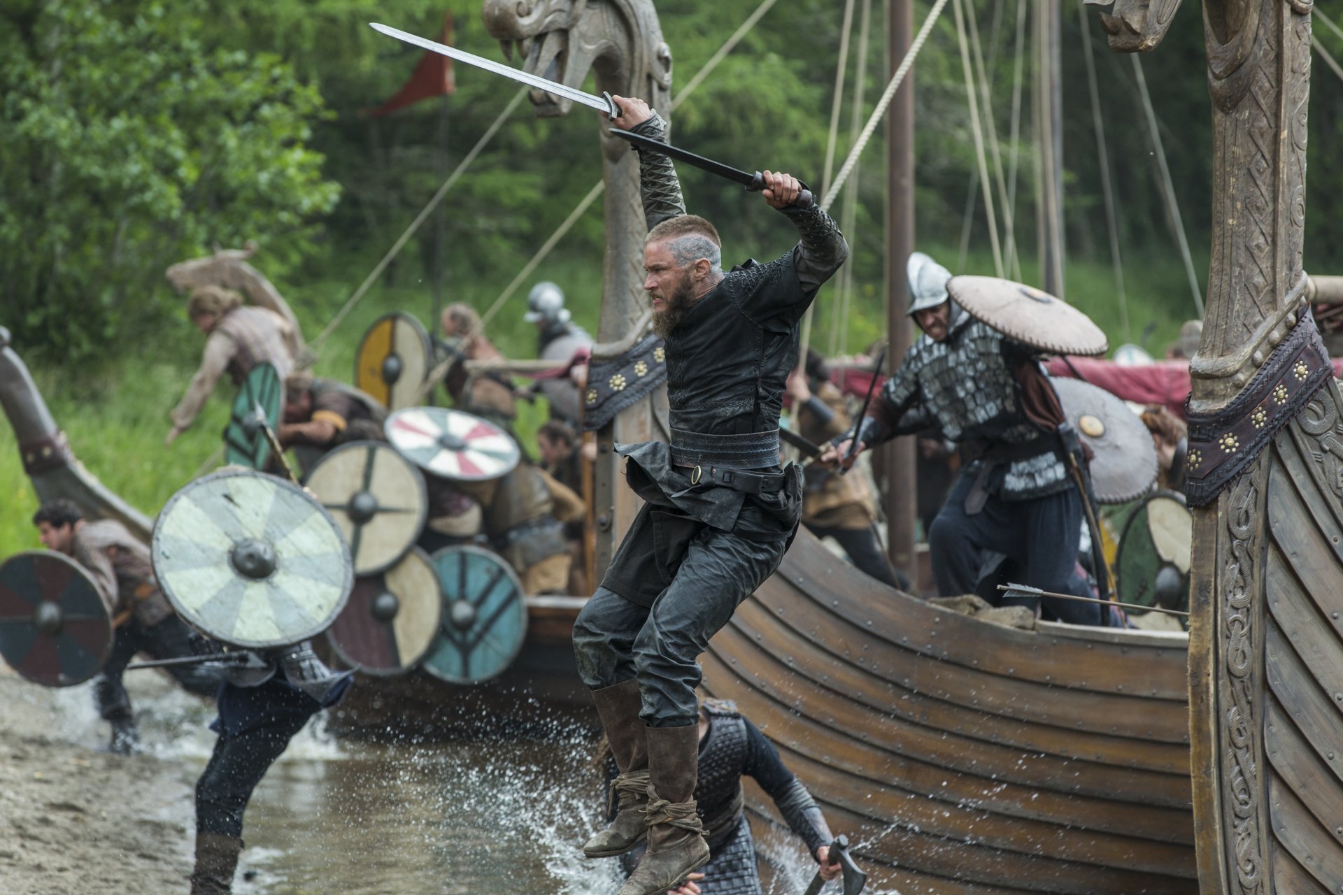 Ragnar Lothbrok (Vikings, 2013) leaping from a longship into battle with sword raised — 5K Ultra HD PC desktop wallpaper background.