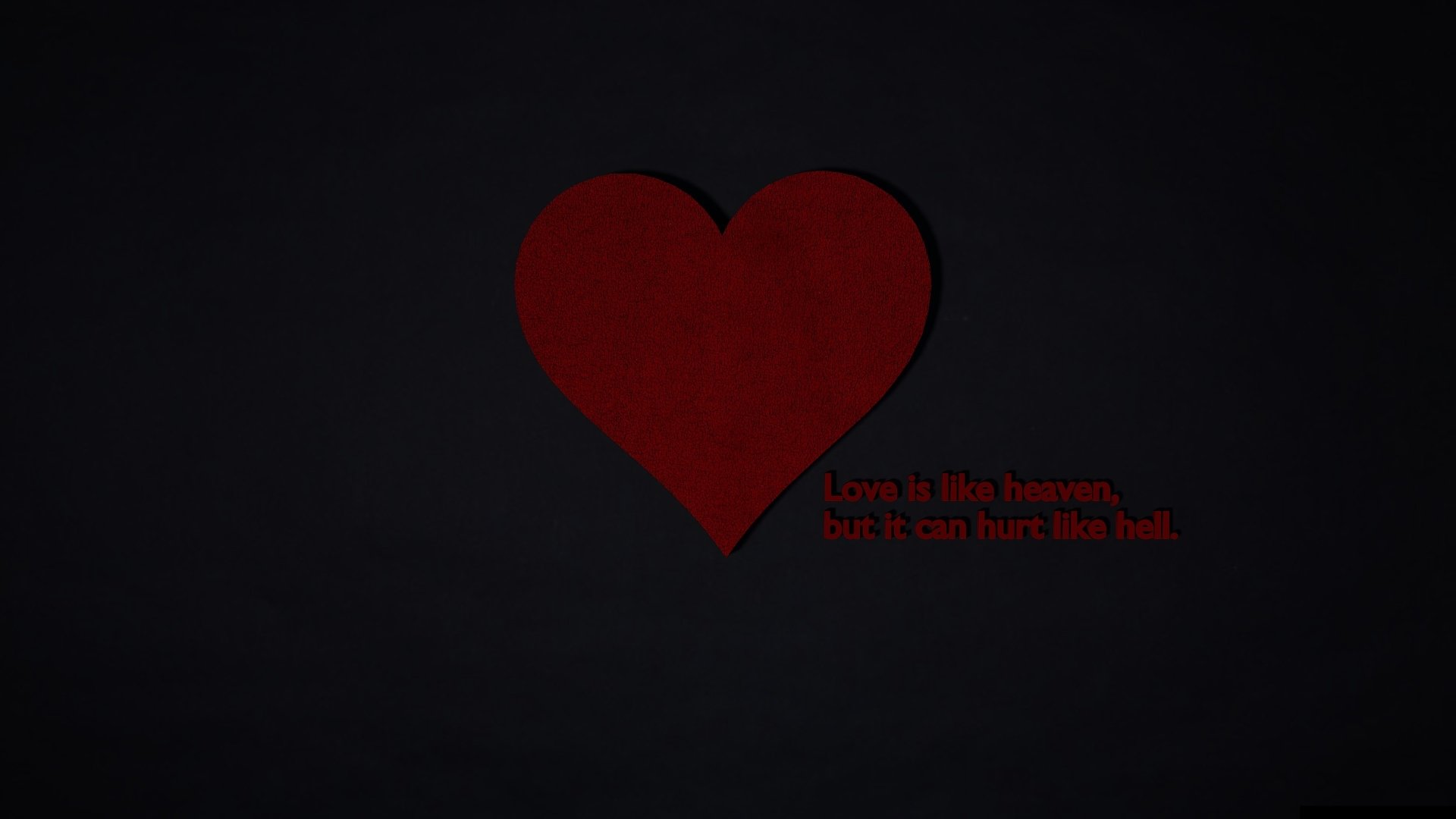 An HD desktop wallpaper with an artistic red heart on a dark background, accompanied by the quote, Love is like heaven, but it can hurt like hell.