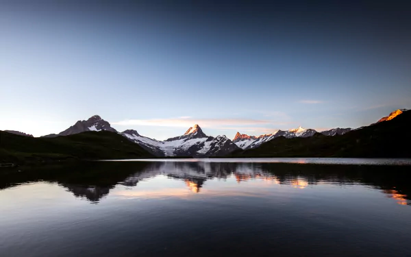 Lake Bachalpsee in Switzerland reflects snow-capped mountains under a clear sky, captured in stunning 4K Ultra HD as a serene nature desktop wallpaper.