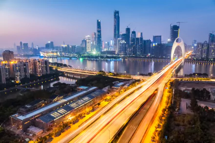 Night time-lapse view of Guangzhou, China: light-trail highway and arched bridge over river, cityscape of glittering skyscrapers — 4K Ultra HD desktop wallpaper.