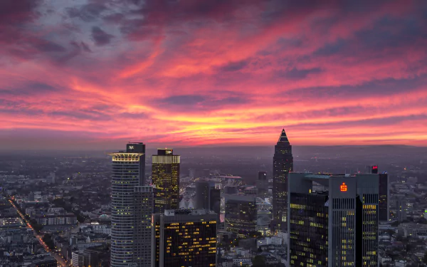 HD desktop wallpaper of Frankfurt, Germany — man-made skyline of skyscrapers and buildings against dramatic pink-orange sunset clouds on the horizon.