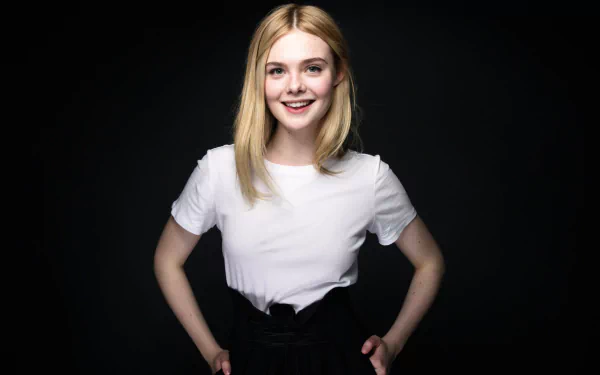 An HD desktop wallpaper featuring American actress Elle Fanning, smiling with green eyes and blonde hair, against a dark background. She is wearing a white top and black skirt.