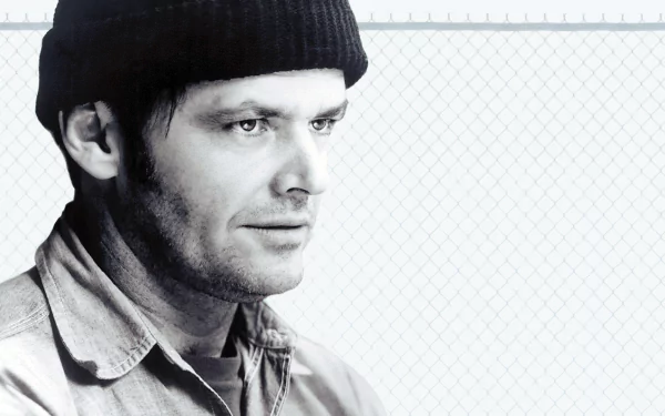Black-and-white HD desktop wallpaper: close-up of a man in a knit cap against a chain-link fence, evoking the film One Flew Over the Cuckoo's Nest.