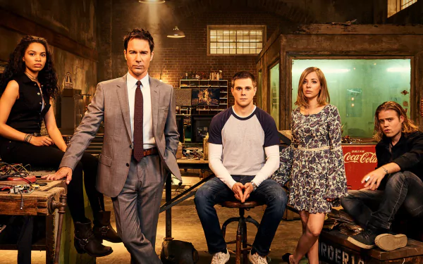 HD desktop wallpaper: five characters from the TV series Travelers pose in a dim, industrial workshop with moody lighting and vintage props.