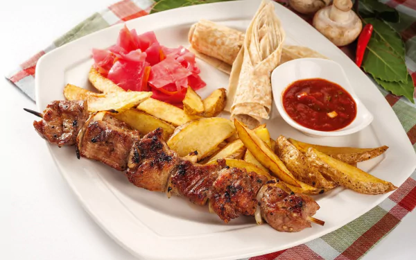 HD desktop wallpaper of a meal featuring barbecue meat skewers, French fries, tortilla, pickled vegetables, and a side of dipping sauce on a white plate.
