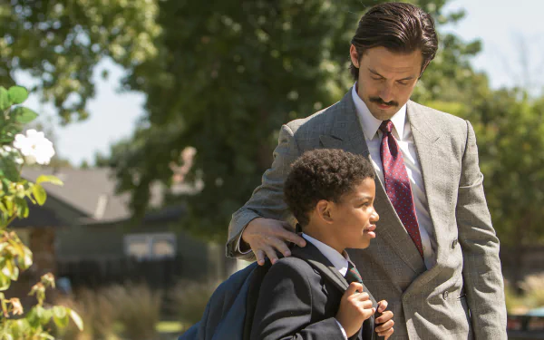 HD PC desktop wallpaper of a scene from the TV show This Is Us: a suited man gently places a hand on a schoolboy's shoulder as they stand outside.