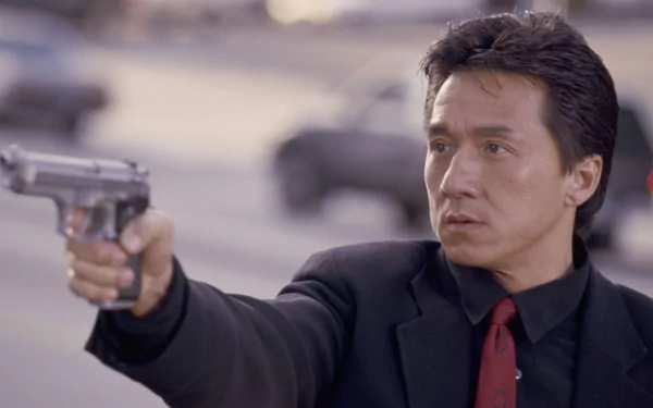 HD desktop wallpaper featuring Jackie Chan in a scene from the movie Rush Hour, holding a gun with a serious expression.