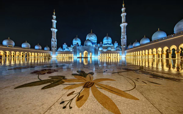 Illuminated Sheikh Zayed Grand Mosque in Abu Dhabi, UAE, showcasing its domes, minarets, and intricate courtyard lighting against the night sky.