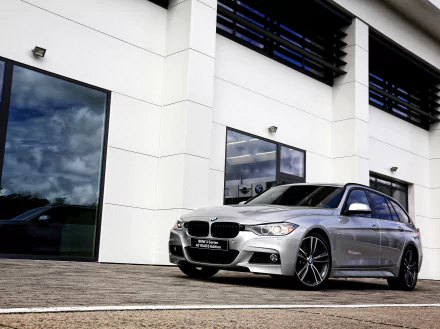 Silver BMW 3 Series parked beside a modern white building, sporty car captured as a 2K Quad HD PC desktop wallpaper/background.