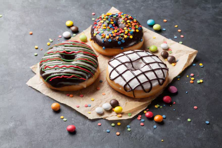 A vibrant 4K Ultra HD still life of colorful candy and three decorated doughnuts on parchment, set against a dark textured background.