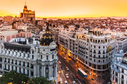 Sunset aerial view of Madrid, Spain, ornate architecture and curved buildings along Gran Vía; man-made cityscape rendered as a 2K Quad HD PC desktop wallpaper background.