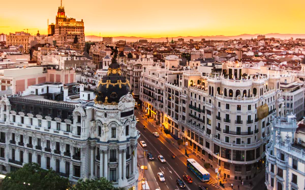 Sunset aerial view of Madrid, Spain, ornate architecture and curved buildings along Gran Vía; man-made cityscape rendered as a 2K Quad HD PC desktop wallpaper background.