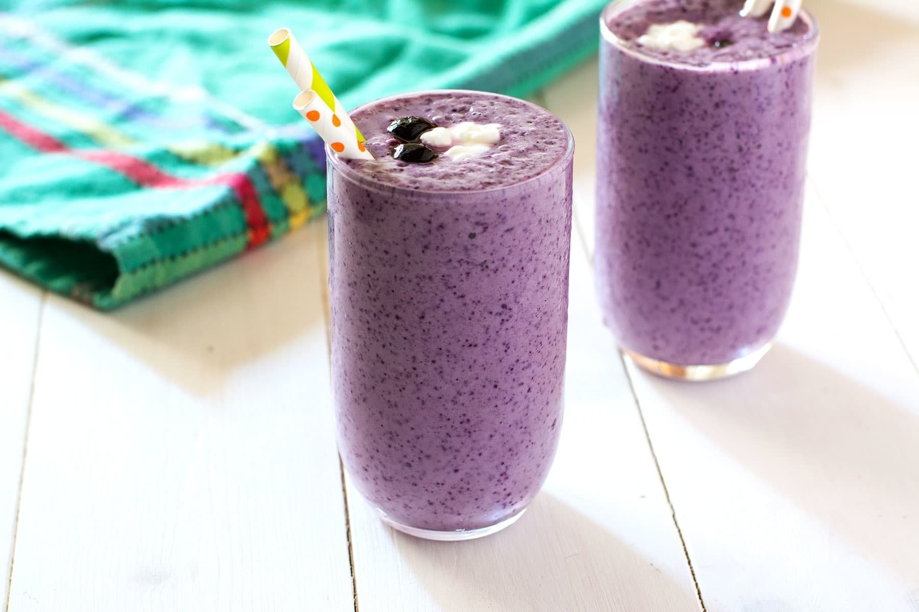 HD PC desktop wallpaper showing two purple berry smoothies in glasses with straws on a white table and colorful napkin — drink, food, smoothie.