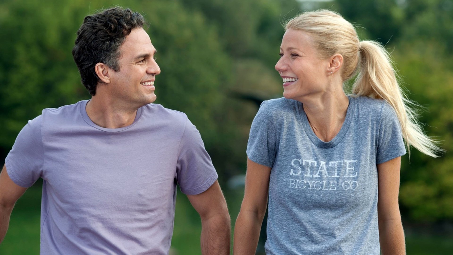 HD desktop wallpaper for the movie Thanks for Sharing showing two actors jogging and laughing together in a green park setting.