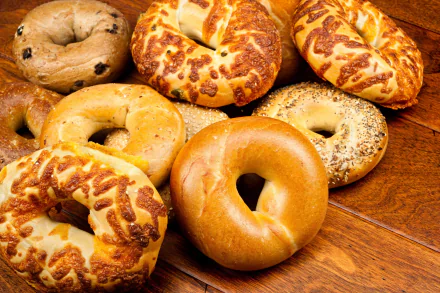 HD PC desktop wallpaper featuring a variety of fresh bagels with different toppings arranged on a wooden surface, highlighting bread and food themes.