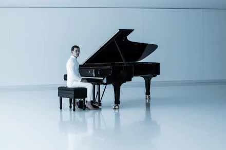 Michael Fassbender in a minimalist white room playing a grand piano, featured in Alien: Covenant, presented as a 4K Ultra HD PC desktop wallpaper.