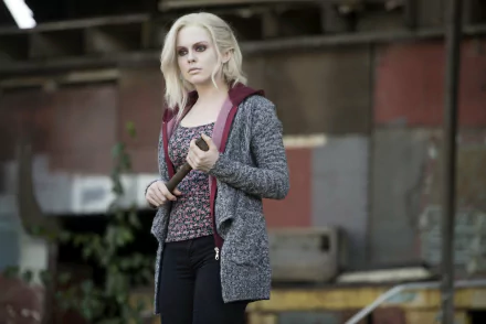 Pale young woman in a hoodie and patterned top holds a bat in an abandoned industrial lot — TV show character wallpaper, 2K Quad HD desktop background.