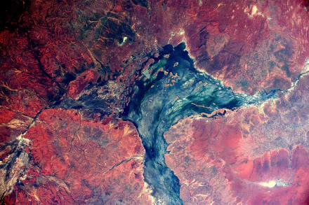 Aerial photography of a lake surrounded by rugged, reddish terrain, featured as a vibrant HD PC desktop wallpaper and background.