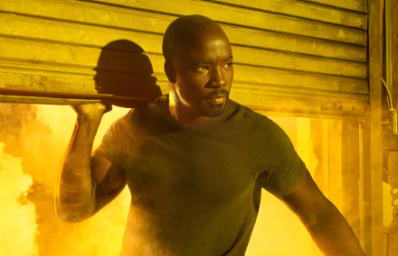 HD desktop wallpaper featuring Mike Colter as Luke Cage from the TV show The Defenders, set against a smoky, industrial yellow-lit background.