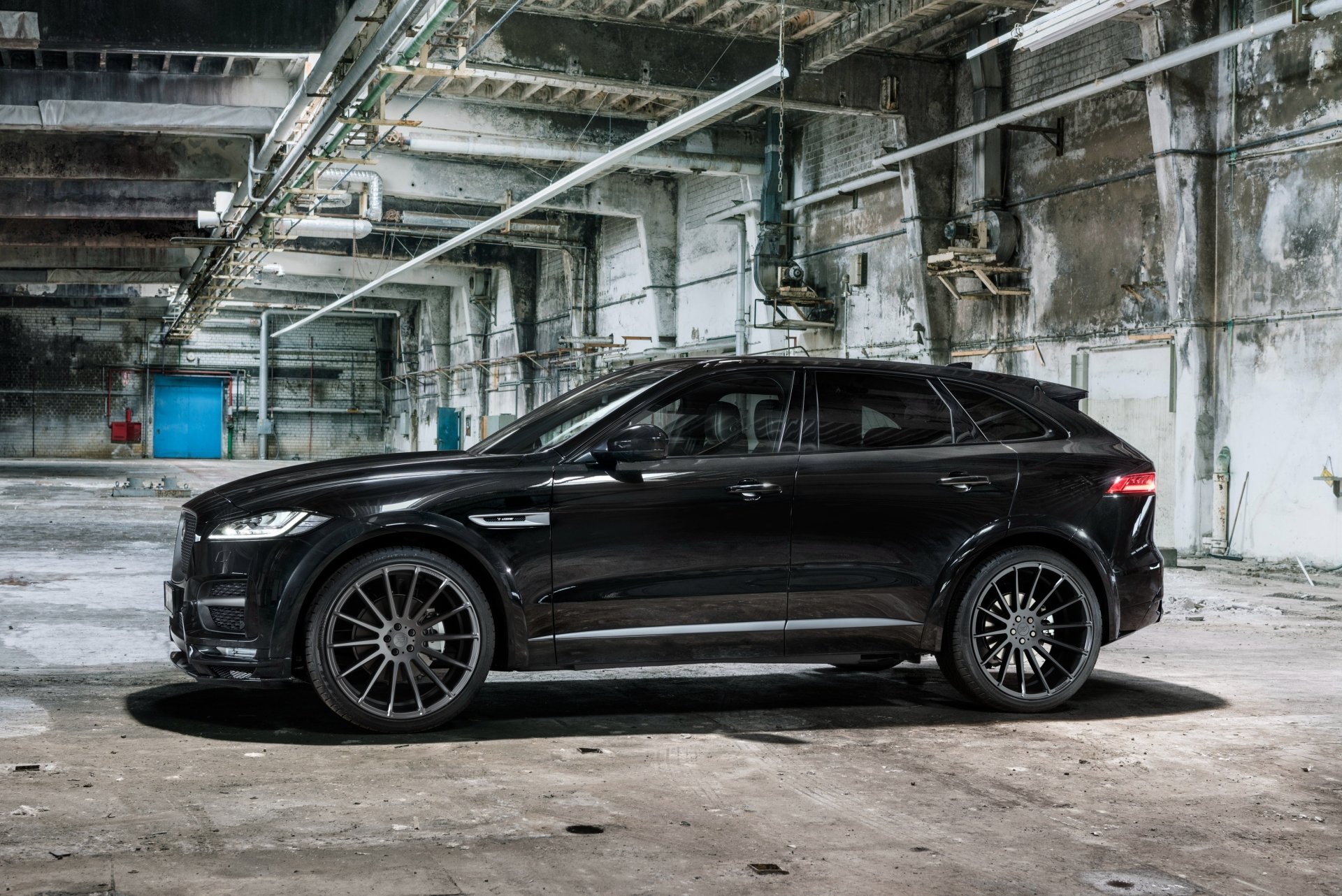 A black Jaguar F-PACE SUV parked in an industrial, weathered warehouse, captured in 4K Ultra HD for a PC desktop wallpaper.