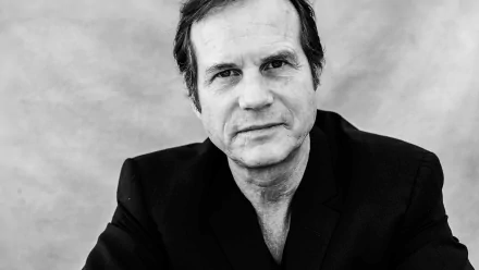 HD desktop wallpaper featuring a monochrome portrait of a man in a black jacket against a plain background.