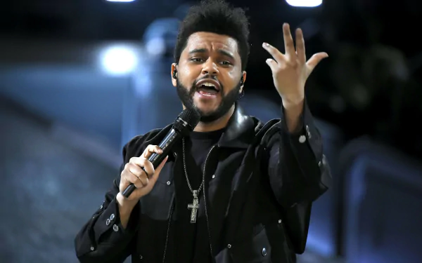 HD desktop wallpaper featuring a person with a microphone in mid-performance, expressive with one hand raised.