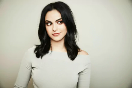 HD wallpaper of Camila Mendes, Brazilian actress with black hair and brown eyes, posing against a light background.
